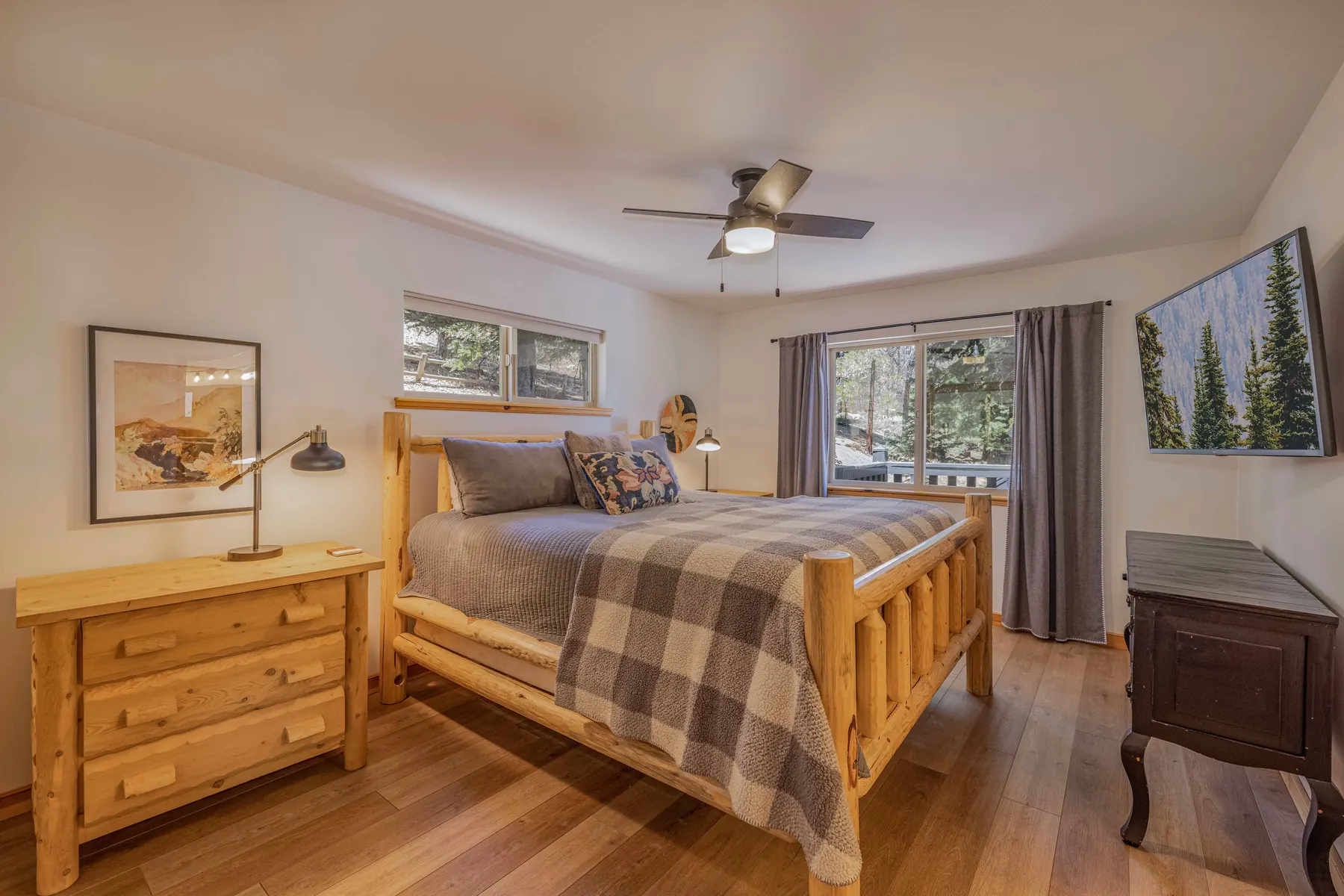 Primary bedroom at Pine Grove Cabin showing the king log bed, dresser, and mirrored closet