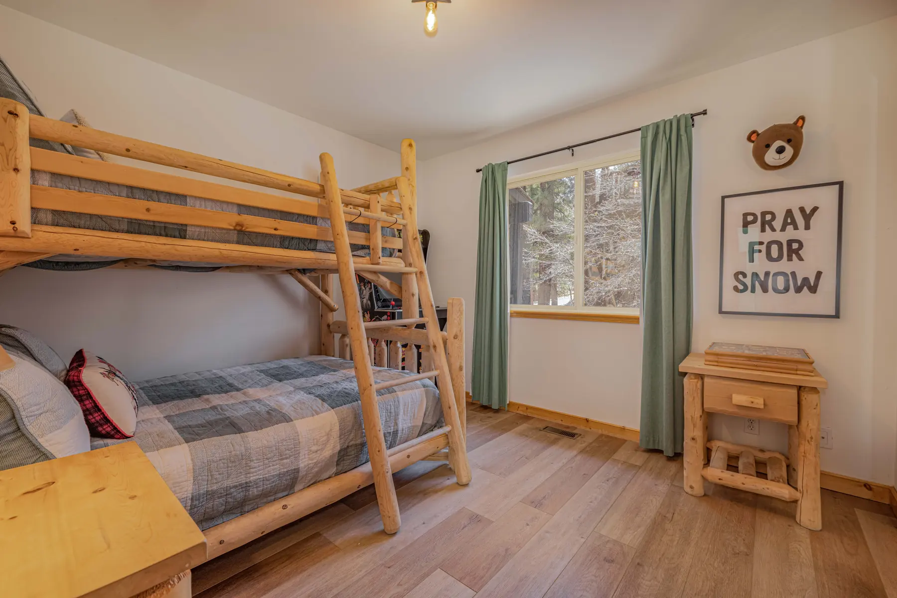 Bedroom Three at Pine Grove Cabin with a log bunk bed and Pray For Snow wall art