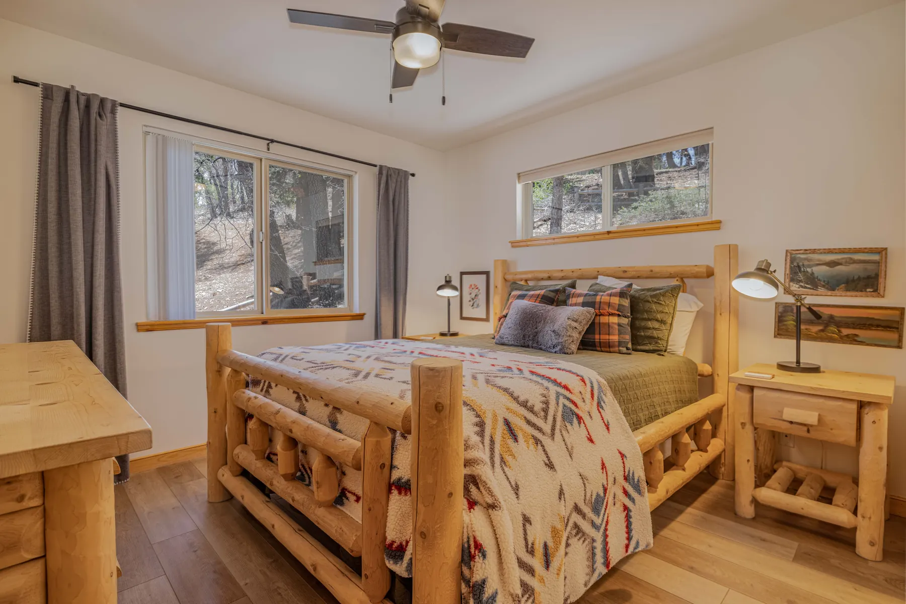 Bedroom Two at Pine Grove Cabin with a queen log bed, plaid pillows, and forest-view windows
