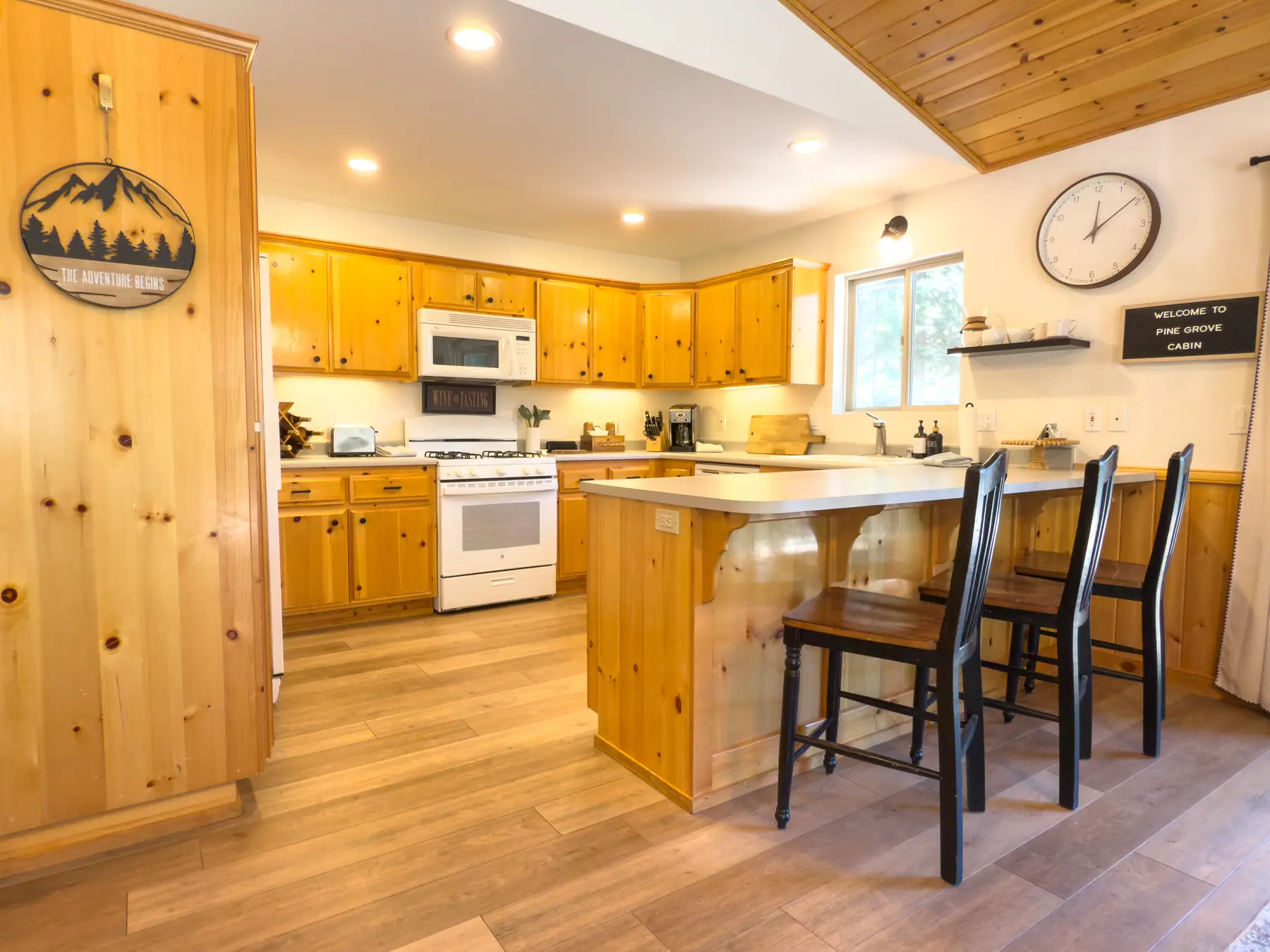 Kitchen at Pine Grove Cabin with knotty pine cabinetry, white refrigerator, and gas range